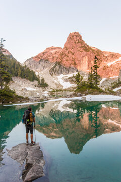 Hiker looking at mountain reflection in alpine lake