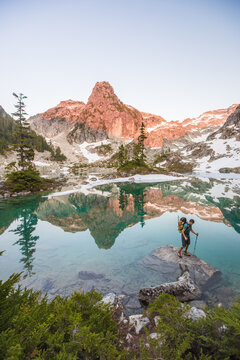 Man explores pristine alpine lake with mountain reflection