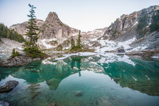 Clear turquoise lake reflecting snow capped mountains