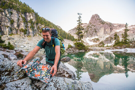 Smiling hiker sets up camp seat by alpine lake