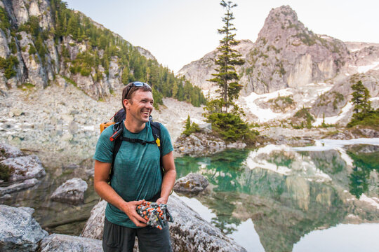Happy hiker smiles by a beautiful alpine lake