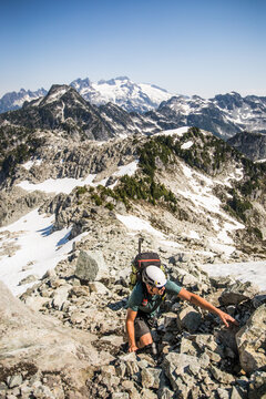Male climber scrambling up a rocky mountain slope