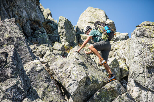 Man rock scrambling on a sunny mountain peak