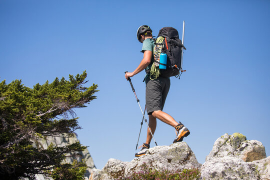 Male hiker scrambles over rocks on sunny day