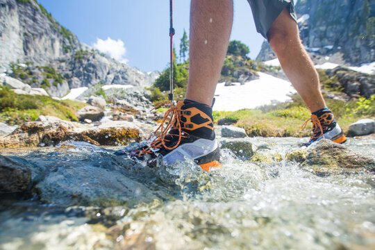 Man in hiking boots crossing a shallow mountain stream