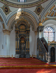 Obraz premium Interior of Aziziye Mosque, Konya, Turkey. Grand mihrab and minbar with intricate gold calligraphy, marble, and red prayer carpet. Sunlight illuminates the ornate details