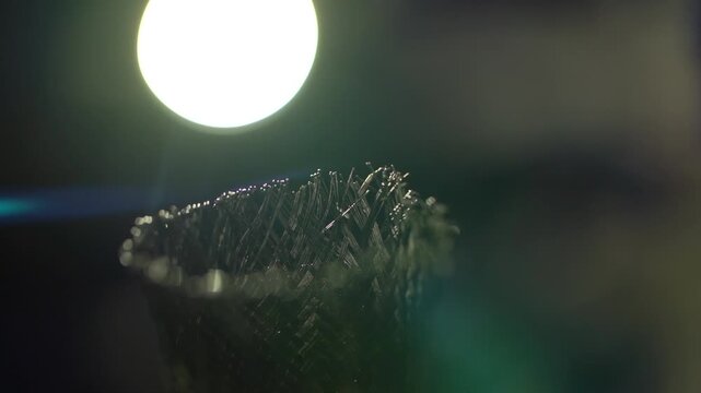 Metallic net ends melting from glowing lamp when approaching heat source.