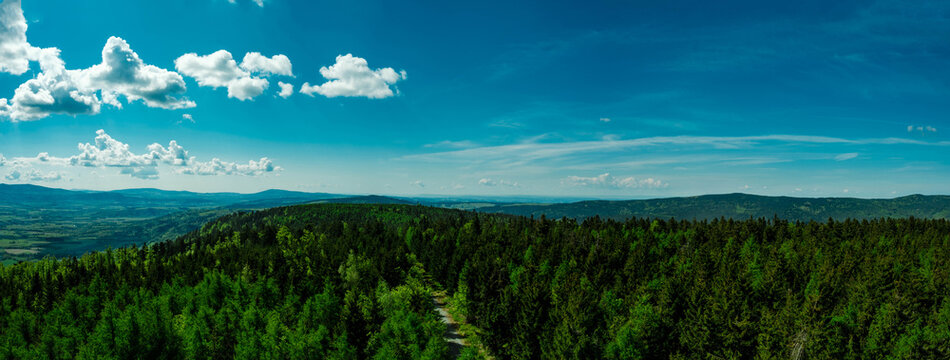 Panorama of a mountain forest with a blue sky and clouds. Sudetes, Sudety.