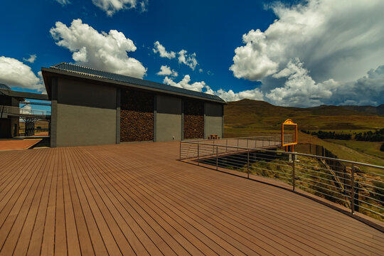 View of a modern building with a spacious wooden deck overlooking the rolling hills and mountainous landscape near Maletsunyane Falls in Maseru, Lesotho.