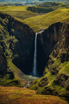 View of Maletsunyane Falls plunging into a deep rocky gorge surrounded by lush green hills and steep cliffs in Maseru, Lesotho.