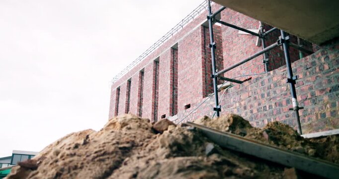 Building, empty or rubble on construction site with scaffolding, urban development or renovation. Low angle, space or infrastructure on worksite for revamping project, engineering design or brickwork
