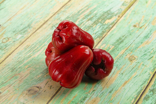 Fresh red wax apples on rustic green wooden table