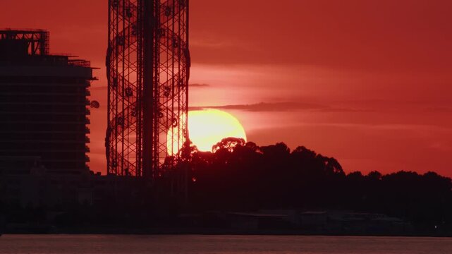 Timelapse of sun setting on red sky in resort town on seashore.