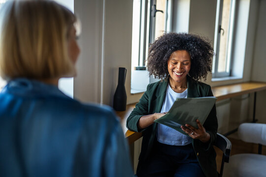 Happy businesswoman collaborating with colleague on business report