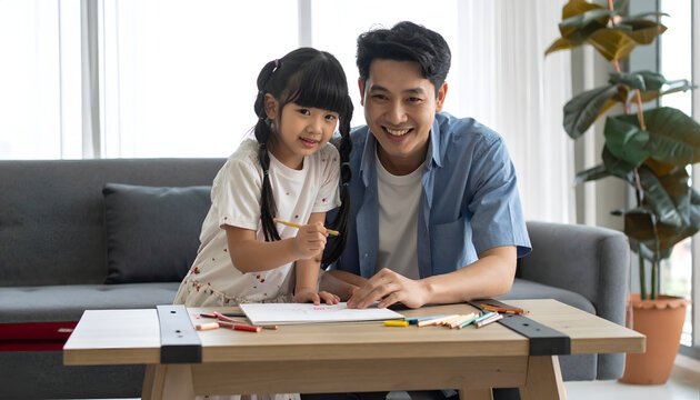 Asian father and young daughter drawing at home together