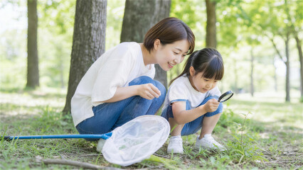 Fototapeta premium 公園で虫眼鏡を使って昆虫観察をする日本人親子