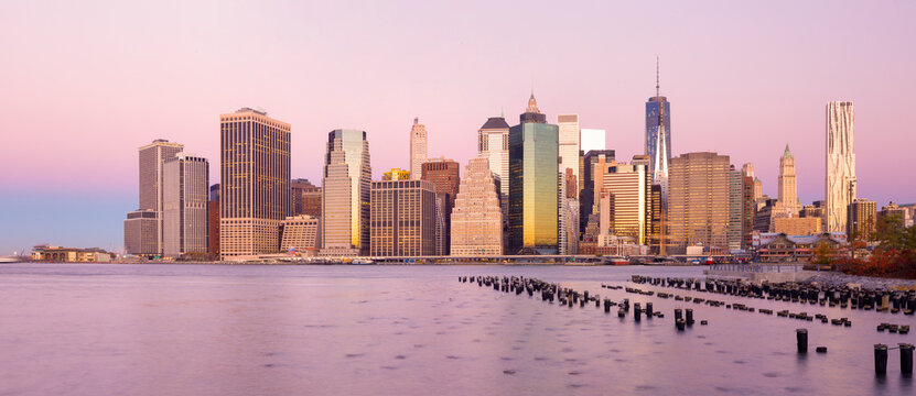 Manhattan skyline skyscrapers reflect sunset light across the East River waterfront, showcasing a premier tourism and urban exploration destination, Lower Manhattan, New York City.