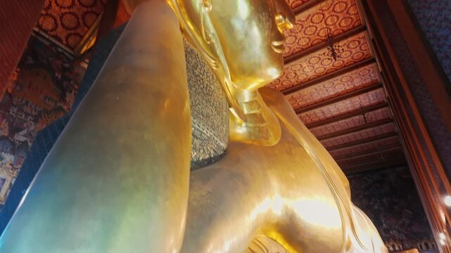 The Reclining Buddha at Wat Pho in Bangkok, Thailand, is a magnificent golden statue representing the Buddha in his final nirvana. This iconic landmark draws pilgrims and tourists alike.