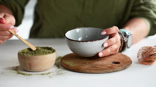 Woman Making Matcha Tea By Scooping Tea Into A Bowl With A Measuring Spoon Close-Up