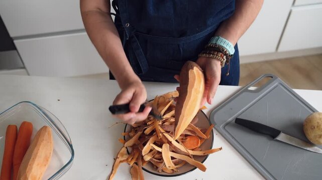 Woman Peeling A Raw Sweet Potato In A Closeup Top-Down View