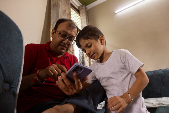 father and son scrolling through smart phone