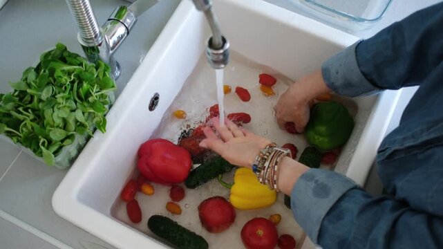 View From Above Of A Woman Washing Red Pepper Over The Sink