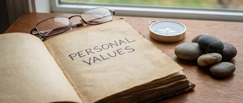 Personal values handwritten in an old book, a compass and river rocks representing ethics and moral guidance