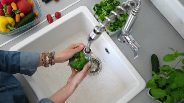 Woman Washing A Green Pepper Over The Sink