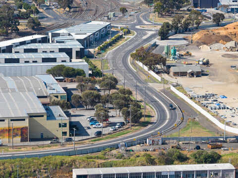 Aerial view of a two laned road winding through warehouses in an urban industrial area