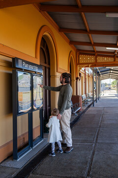 man with daughter looking at plan you trip sign at train statin platform in Armidale