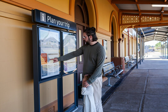 man with daughter looking at plan you trip sign at train statin platform in Armidale