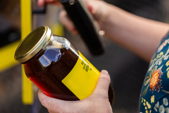 Aussie woman choosing jar of honey to buy at local small businesses roadside stall