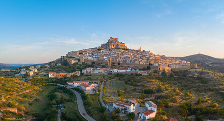 Panoramic view of Morella, medieval walled town with hilltop castle at sunrise, vineyard terraces and valley landscape, Els Ports, Castellon, Valencian Community, Spain © VantagePerspective