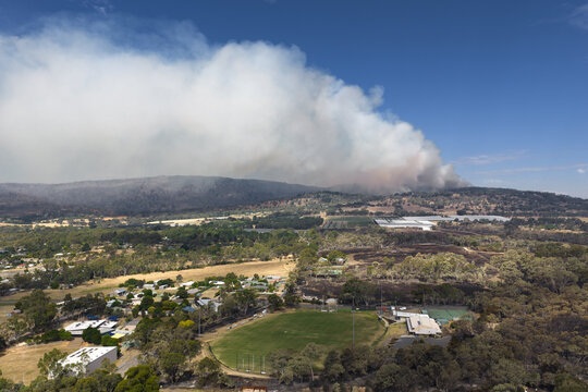 Aerial view of a large bushfire burning on a distant hillside behind a country town