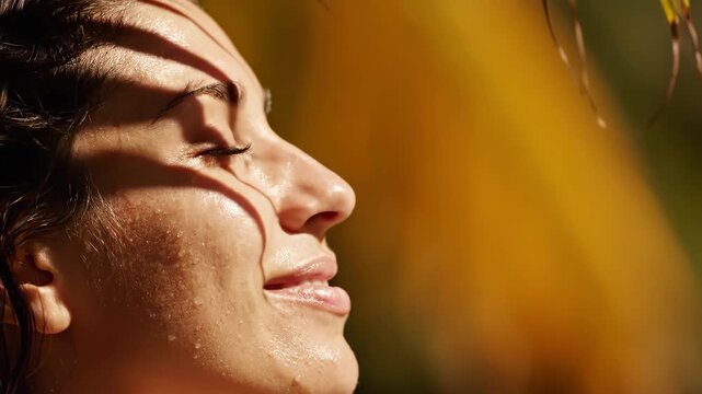 Woman relaxing in sunlight outdoors. Extreme close-up of female face with shadows on skin. Wellness and skincare concept, natural lighting for beauty industry