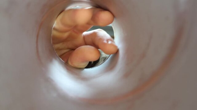 View from inside food container as person reaches with fingers searching for remaining snack pieces and trying to grab the last bite from the bottom