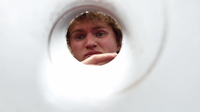 View from inside drain pipe as person checks for blockage and inspects water passage searching for cause of slow drainage before maintenance work