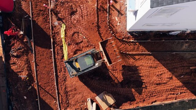 Topdown Aerial View Of Compact Track Loader Leveling Red Clay Soil At Residential Construction Site. static shot