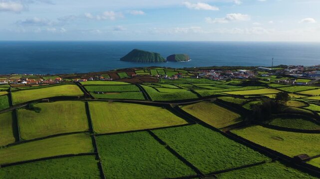 Patchwork Of Lush Green Farm Fields Separated By Stone Walls Overlooking The Ilheus das Cabras In Terceira Island, Azores, Portugal. - aerial shot