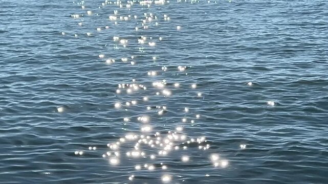 Shimmer water wide background, summertime calm sea with glow from the sun, loop video