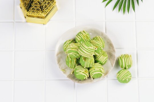 Green pandan flavored nastar cookies arranged on plate with decorative background.