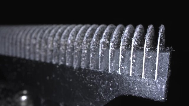 A close-up shot of an electric razor blade in macro mode, revealing skin and hair particles