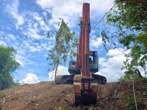 The backhoe is digging the ground.