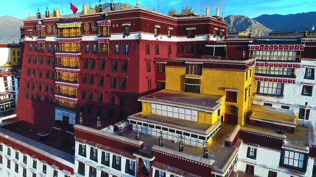 Aerial view of the Potala Palace at sunrise in Lhasa, Tibet, China, with the historic palace on the hill overlooking the city, surrounded by mountains and morning mist under golden light.