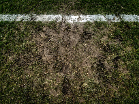 Muddy grass texture with white line aerial view of a sports field