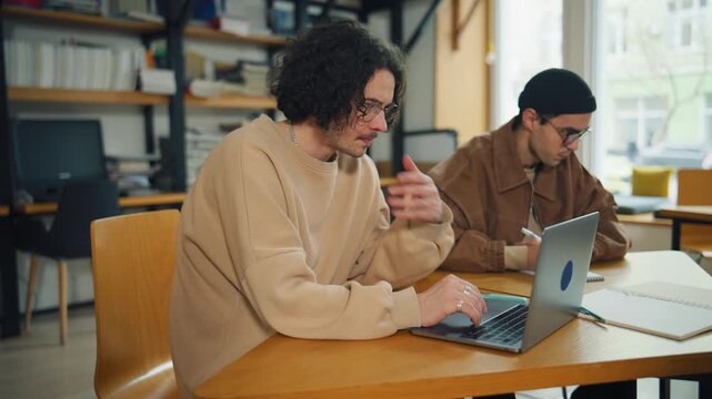 Students work on laptops in a library during study session