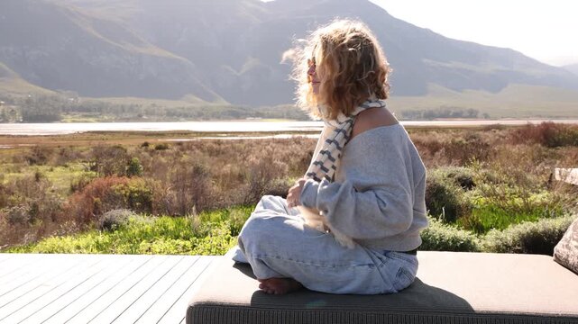 stylish young woman relaxing at resort overlooking Klein Mountains and Lagoon Stanford, South Africa