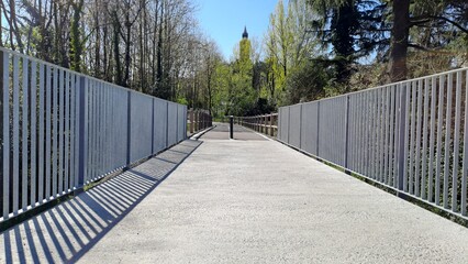 Fototapeta premium A metal footbridge, suitable for pedestrians and cyclists, with a natural backdrop in northern Italy, Europe.