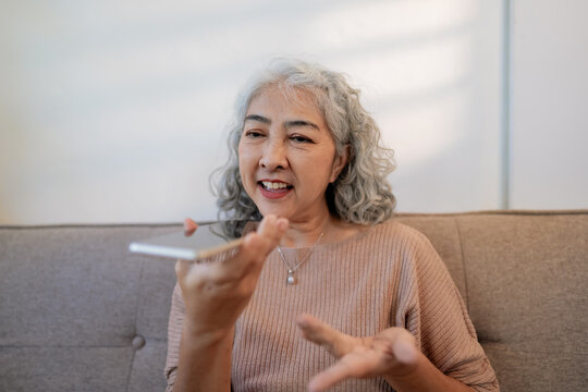 senior woman uses AI voice assistant on smartphone for daily tasks at home