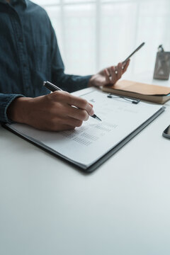 Focused businessman checking reports and verifying office documents with calculator and paper files on table